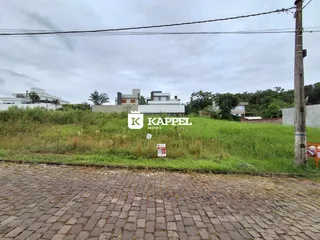 Vista externa da propriedade mostrando o terreno e as construções ao fundo.