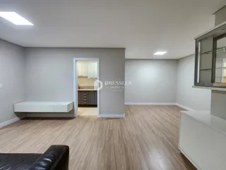 Sala de estar com piso de madeira clara e paredes cinzas.