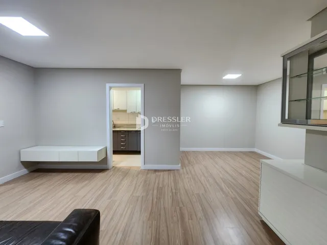 Sala de estar com piso de madeira clara e paredes cinzas.