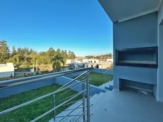 Vista da varanda com grade de metal e paisagem verde.