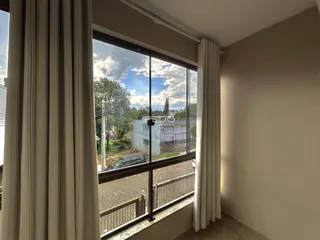 A vista da janela mostra uma paisagem com árvores e água ao fundo.