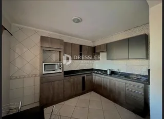 Foto do interior de uma cozinha com armários de madeira e piso cerâmico.
