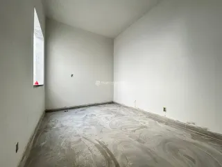 Foto de um cômodo vazio com paredes brancas e piso de concreto.