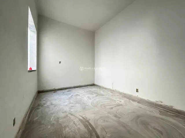 Foto de um cômodo vazio com paredes brancas e piso de concreto.