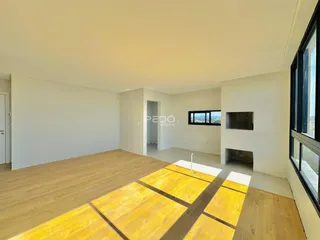 Ambiente interno de uma sala ampla com piso de madeira clara.