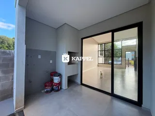 Hall de entrada com piso claro e porta lateral, com vista para outra área iluminada.