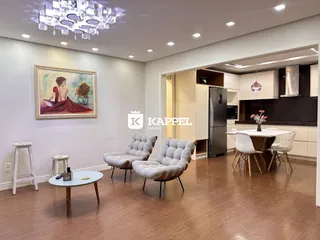 Sala de estar com poltronas e piso de madeira em um apartamento.