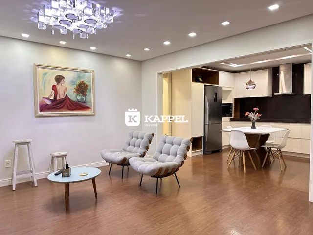 Sala de estar com poltronas e piso de madeira em um apartamento.