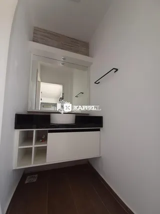 Banheiro com bancada escura e espelho grande.