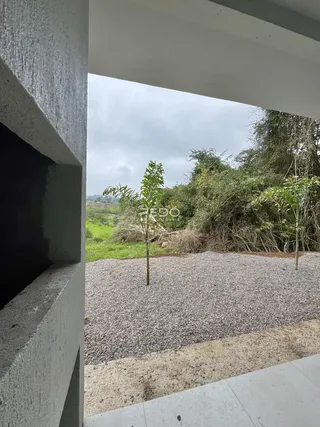 Vista externa de uma propriedade com jardim e vegetação ao fundo.