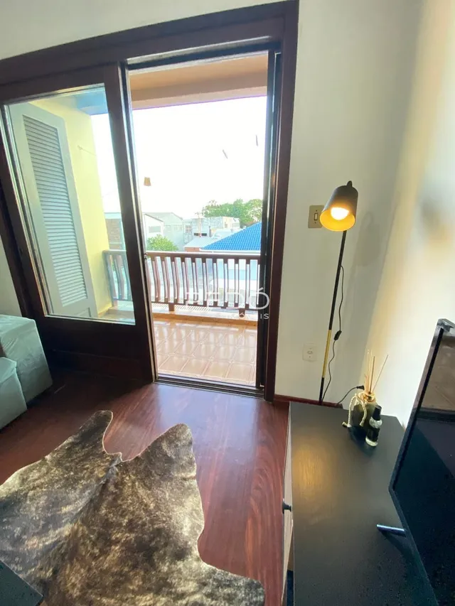 Vista interna de uma sala com piso de madeira e porta de vidro.