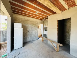 Foto de um espaço interno bruto com paredes de concreto expostas e teto de vigas.