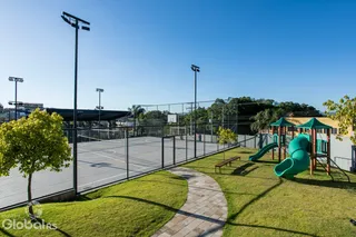 Vista de uma área verde com playground e quadra ao ar livre.