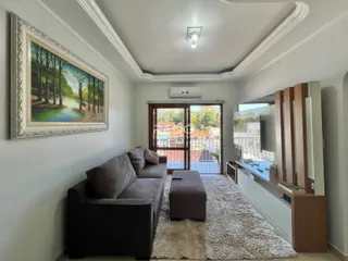 Sala de estar com sofá e televisão em um apartamento no Brasil.