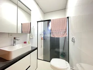 Foto interna de um banheiro moderno com box de vidro.