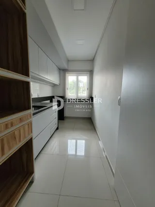 Corredor com armários em madeira e paredes brancas.