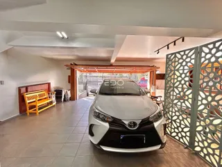 Interior de uma sala com piso de cerâmica e estrutura de madeira que se abre para uma área externa.