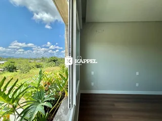 Vista ampla de paisagem verde e céu azul vista pela janela da residência.