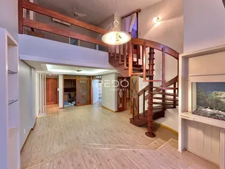 Vista interna de um hall com escadaria de madeira em uma residência.