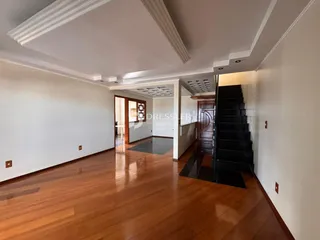 Sala de estar com piso de madeira polida e teto alto.