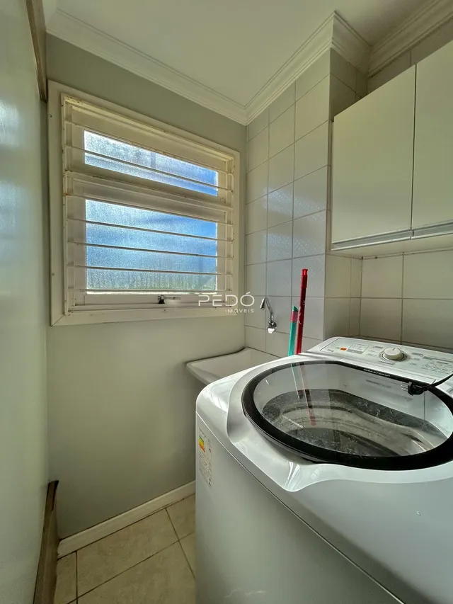 Interior de um banheiro com máquina de lavar roupa e janela.