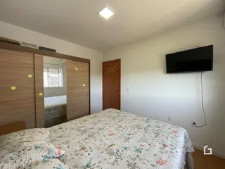 Quarto com armários em madeira e televisão na parede.
