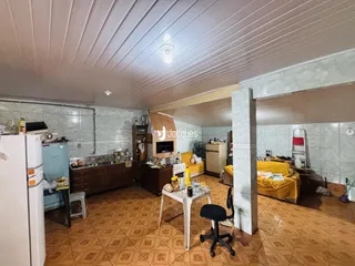Imagem de uma sala de estar com piso de cerâmica e paredes de azulejo em uma residência.