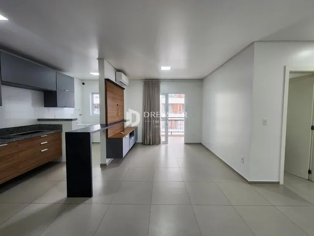 Ambiente moderno de sala de jantar e cozinha com piso de cerâmica clara.