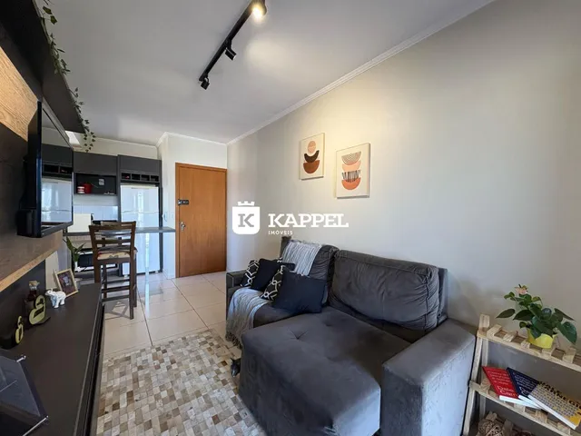 Uma sala de estar com sofá cinza e decoração de parede clara.