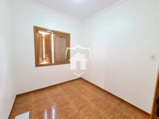 Vista interna de uma sala com piso de madeira clara e parede branca.