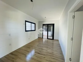 Interior de uma sala com piso de madeira clara e paredes brancas.