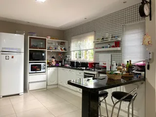 Cozinha moderna com armários brancos e bancada escura.