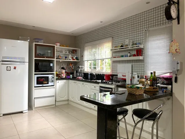 Cozinha moderna com armários brancos e bancada escura.