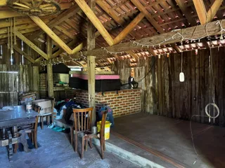 Ambiente interno rústico com vigas de madeira expostas e mesa de jantar.