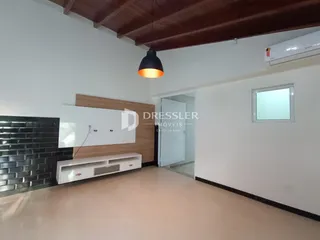 Sala de estar com piso claro e parede de tijolos escuros.