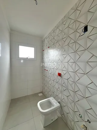 Um banheiro com piso claro e parede decorada com revestimento geométrico.
