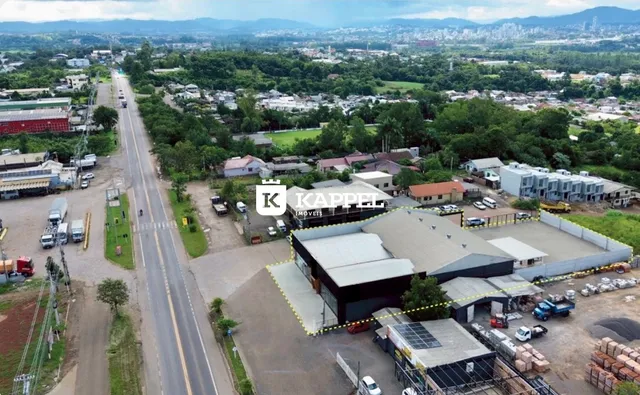 Vista aérea de um complexo industrial com vários galpões e uma estrada.