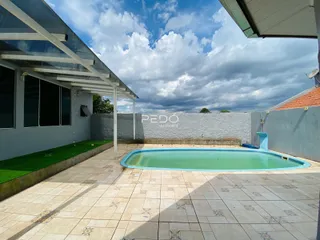 Piscina externa com área de lazer e muro no quintal.