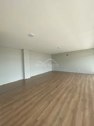 Foto de um ambiente interno com piso de madeira clara e paredes brancas.