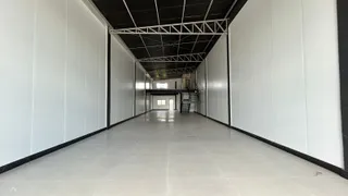 Corredor longo com paredes brancas e piso claro.