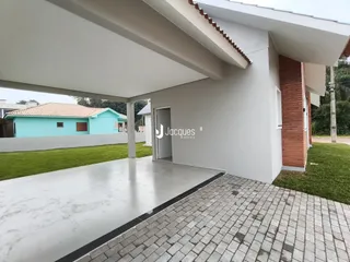 Fachada de uma casa com área externa coberta e gramado.