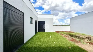 Fachada externa de uma residência branca com gramado verde.