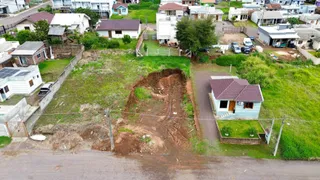 Vista externa de um terreno com terra e uma pequena residência.