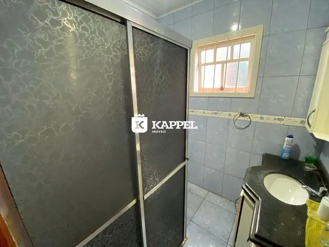 Foto de um banheiro com revestimento de azulejos azuis e uma janela.
