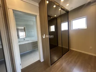 Um corredor com espelho e acesso a um banheiro.