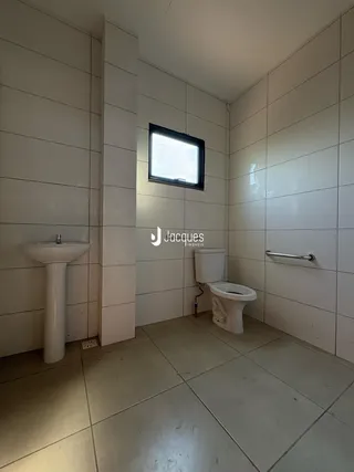Foto de um banheiro com paredes brancas e piso de cerâmica.