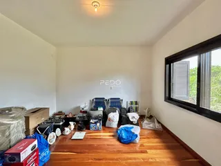 Ambiente interno de uma sala com piso de madeira e janela grande.