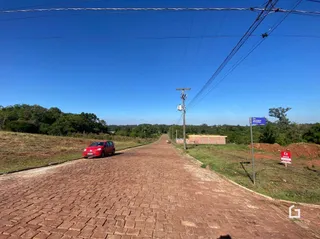 Uma estrada de terra leva a uma área gramada com árvores na propriedade.