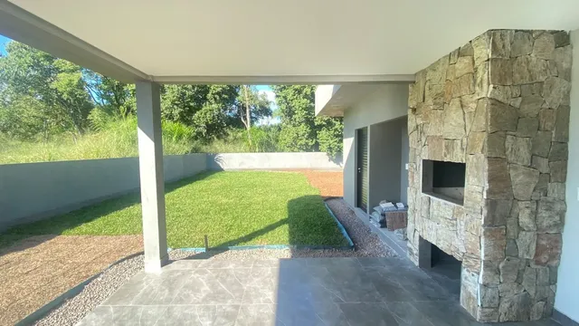 Vista externa de um jardim com gramado e área pavimentada em uma propriedade em Lajeado.