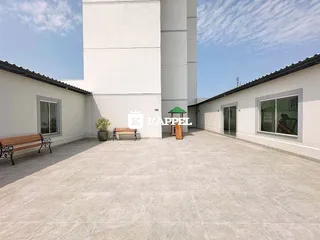 Área externa pavimentada com bancos e um pequeno gazebo.